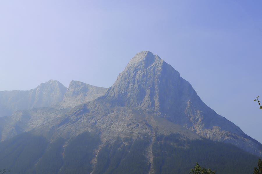 A picture containing a view of Ha Ling mountain peak and hazy blue sky with no clouds